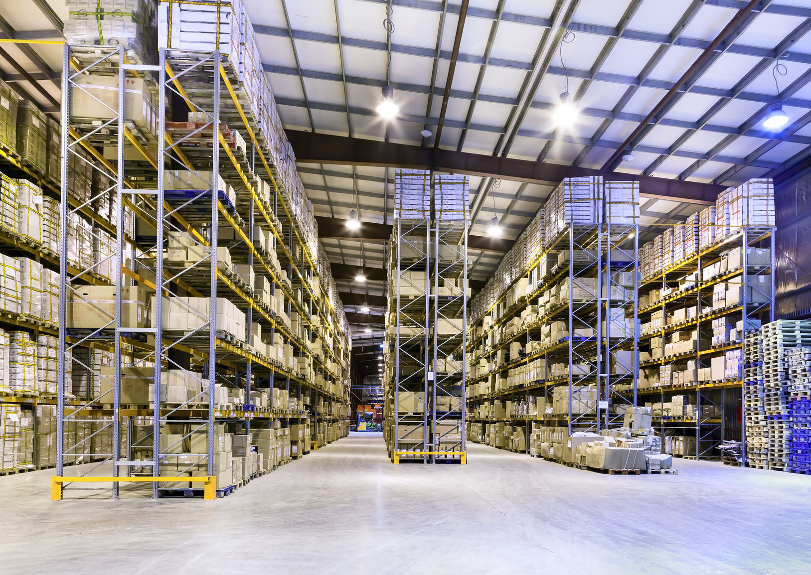 Warehouse Steel Shelving System vs. Wood Shelving: Which is Better? A vast warehouse showcases numerous tall, gray steel shelving units fully stocked with boxes and other materials.