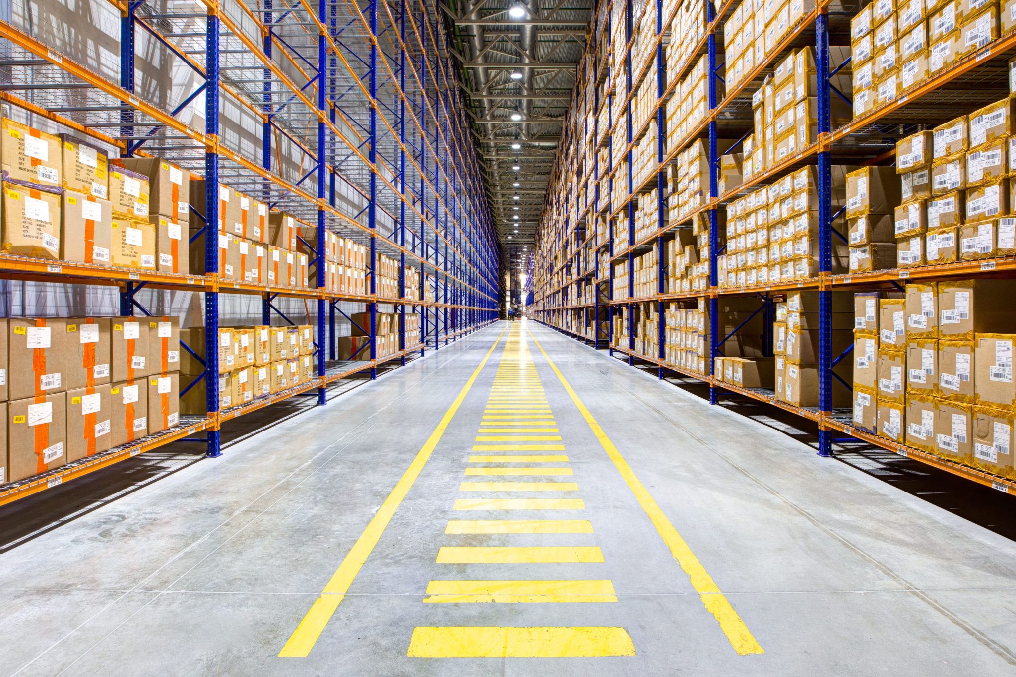 Warehouse Bright, organized warehouse aisle with fully stocked blue and orange pallet racking. High-quality pallet racking systems by Midwest Warehouse Solutions Inc.