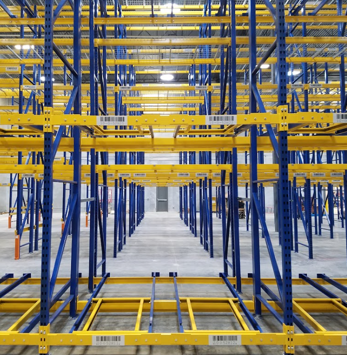 Warehouse An empty warehouse with blue uprights and yellow beams of pallet racking, showing why working with a systems integrator matters.