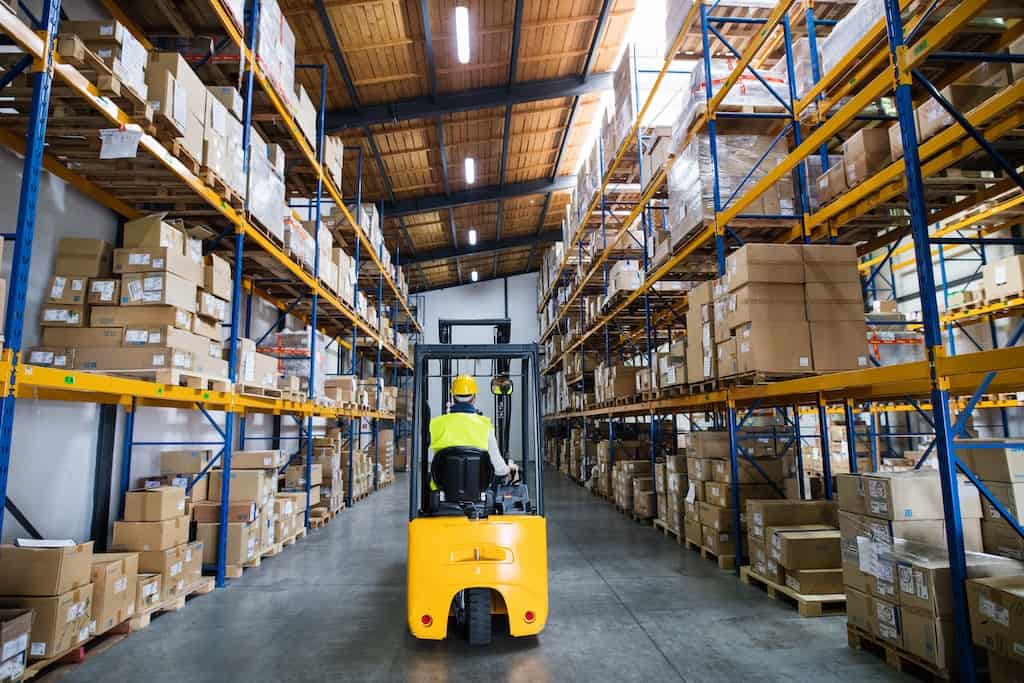 Warehouse Bright warehouse aisle with yellow forklift and stacked boxes on shelves. Mini warehouse storage solutions.