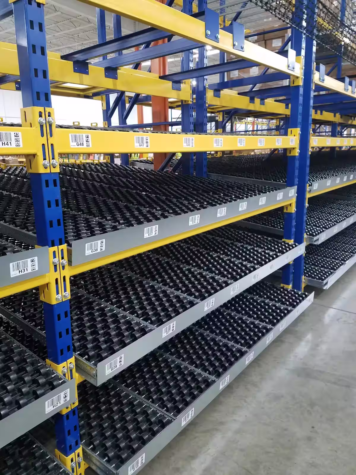 Carton flow racking with rear-loading replenishment aisle separated from pick face