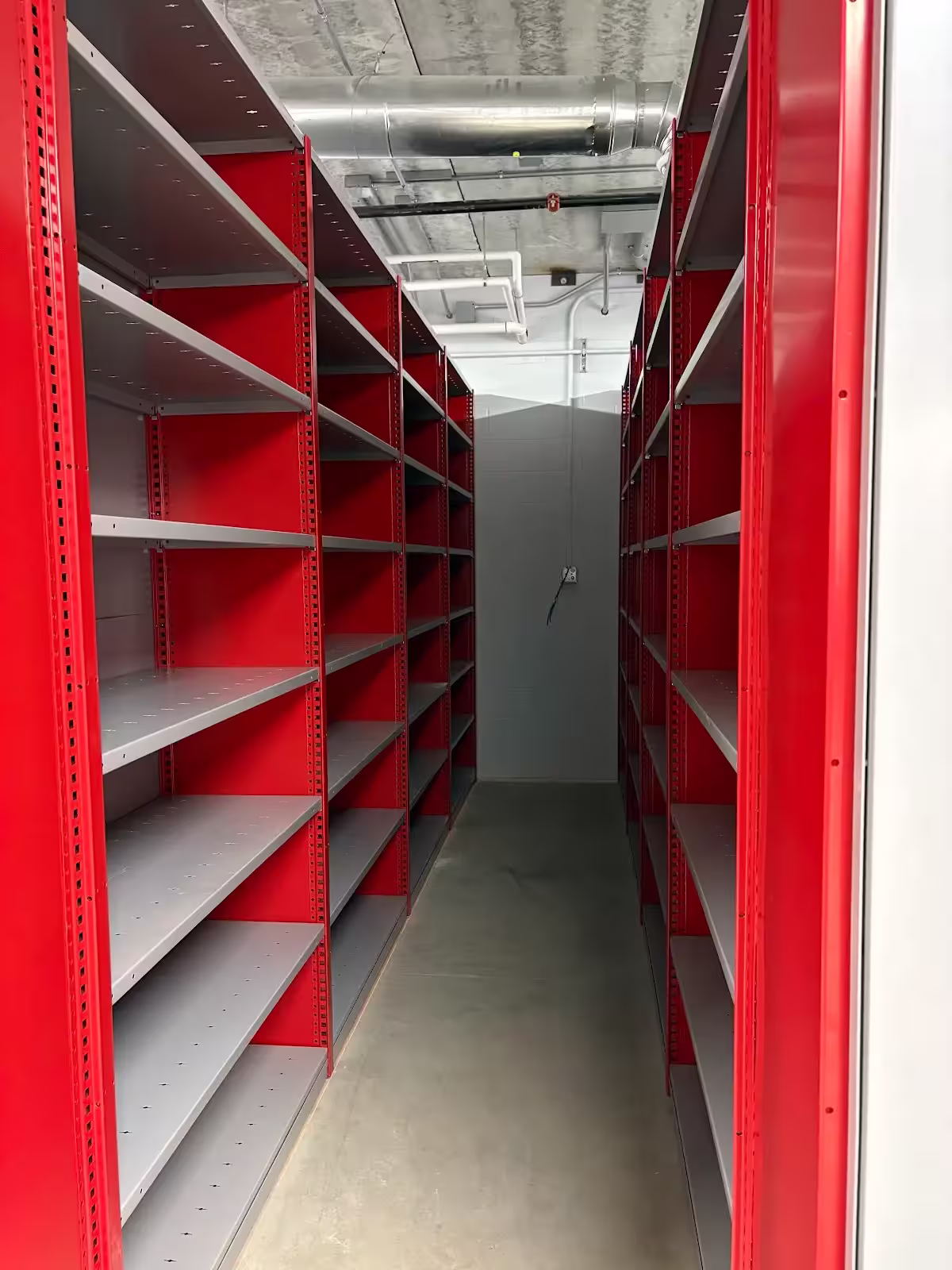Closed industrial steel shelving aisle with adjustable multi-level shelves for warehouse parts and inventory storage